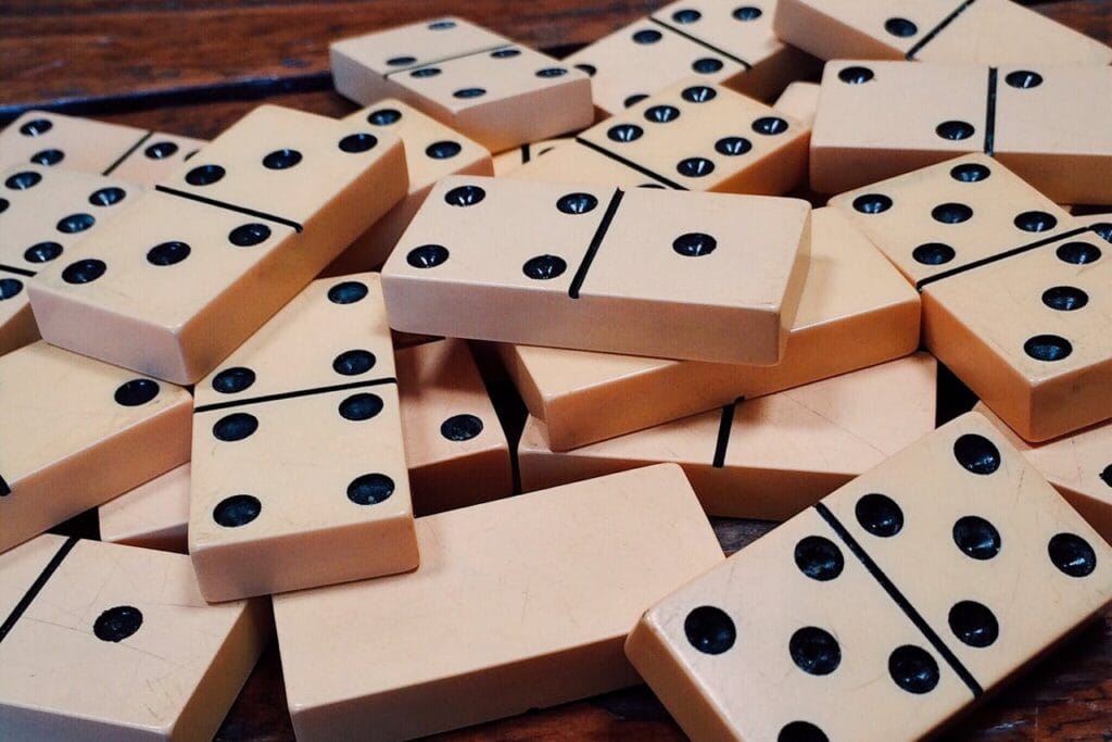 A pile of scattered domino tiles on a wooden table, showcasing numbers and pips for game enthusiasts.
